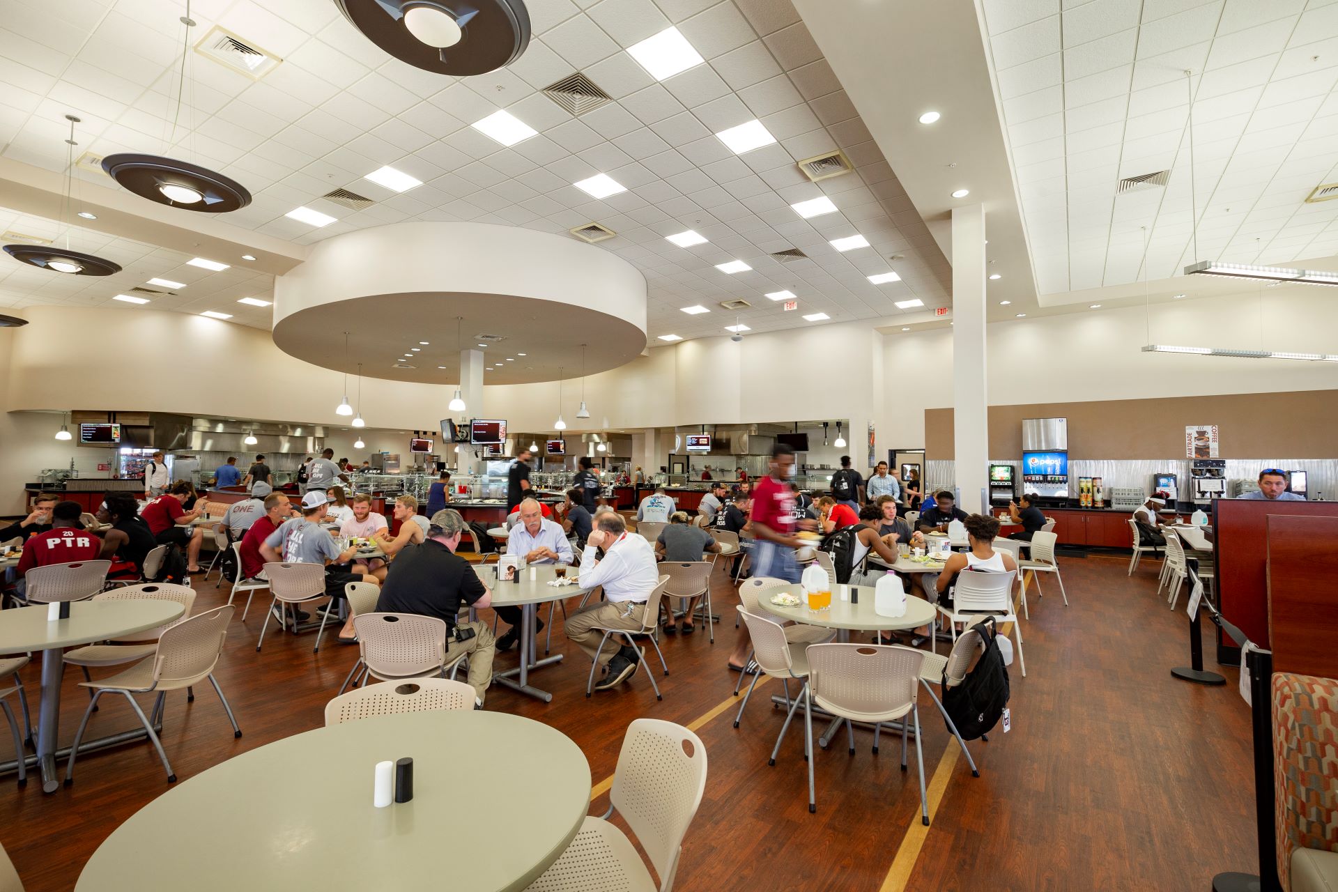Wide view of a busy college dining hall with students and staff seated at tables, eating and conversing